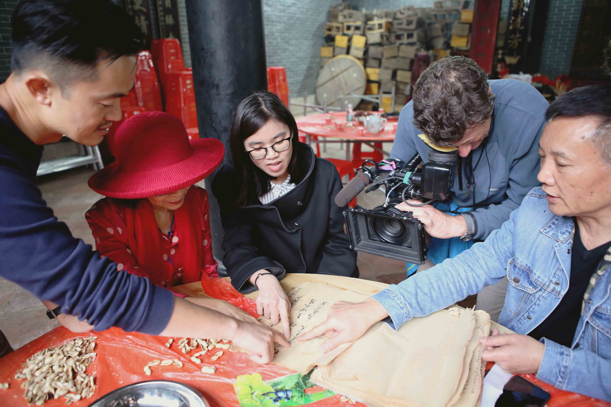 Videographer filming people pointing at an old document