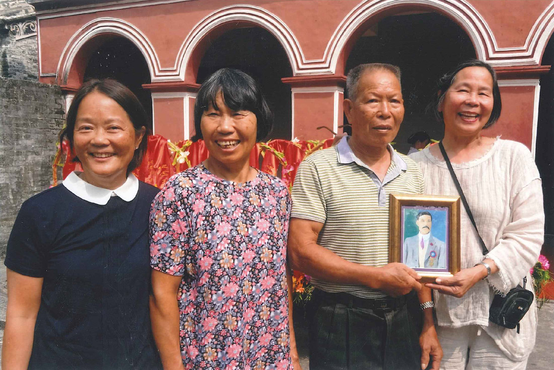 People smiling holding a photo of their ancestor